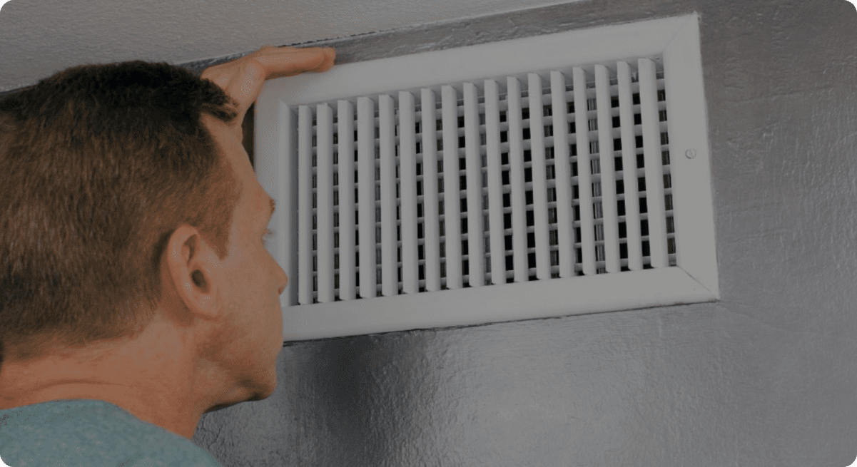 image of a man in his 50's looking at his HVAC vent for dust or dirt
